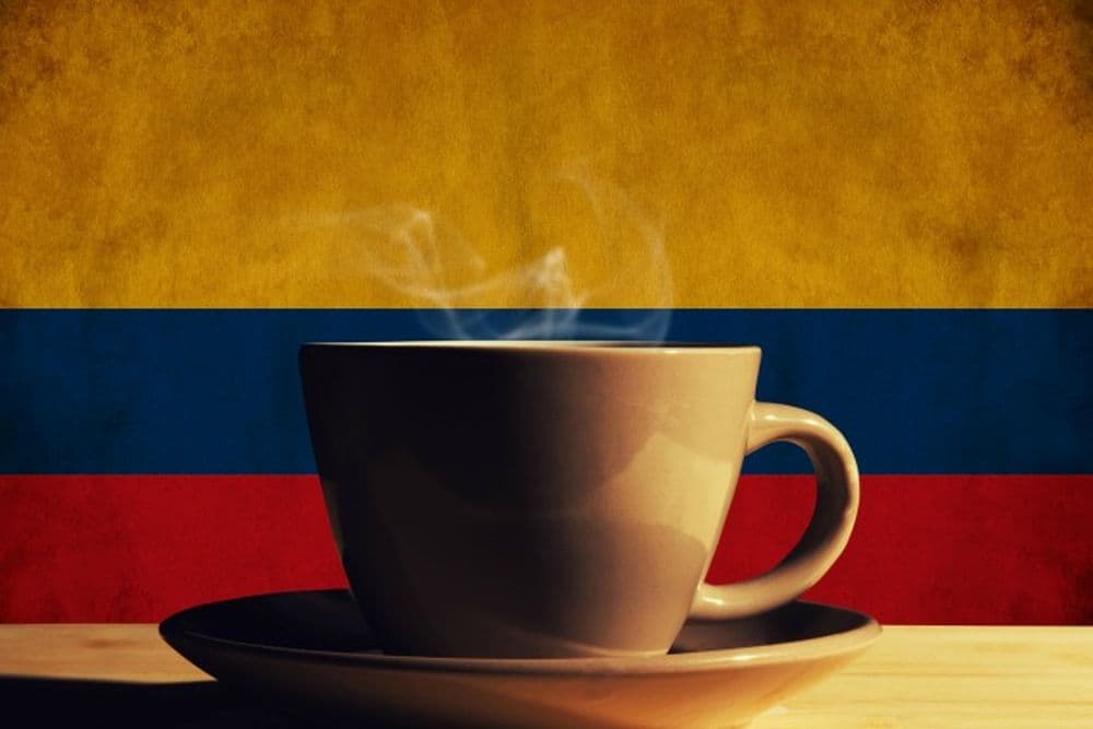 Tasse Kaffee mit kolumbianischer Flagge im Hintergrund