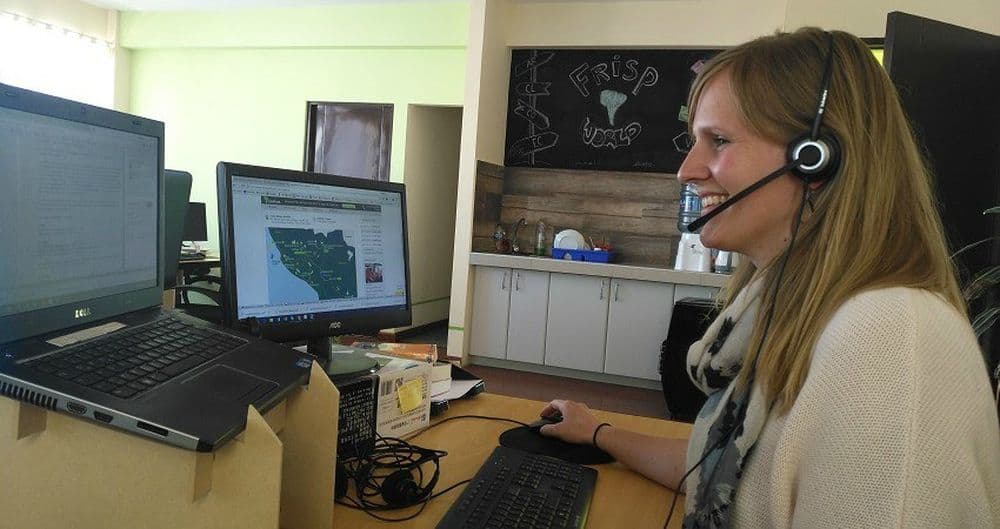 Praktikum in La Paz. Sarah sitzt an ihrem Schreibtisch und spricht mit einem Kunden über ihr Headphone.